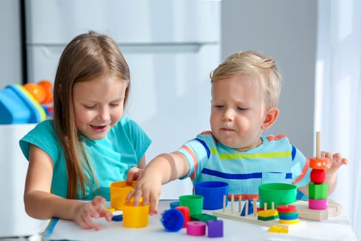 Sister helps little brother to assemble the pyramid. Educational logical toys for children. Montessori games for child development. photo