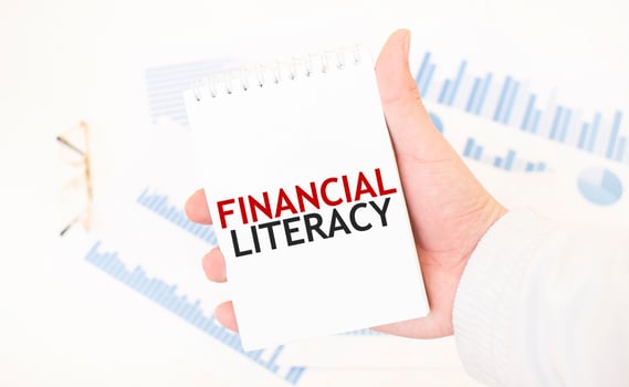 Businessman holding a white notepad with text FINANCIAL LITERACY, business concept photo