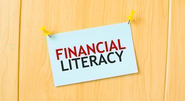 FINANCIAL LITERACY sign written on sticky note pinned on wooden wall photo
