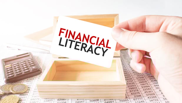 Businessman hold white card with text FINANCIAL LITERACY Calculator, wood box, money and financial documents photo