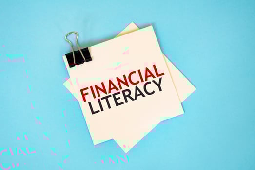 Text FINANCIAL LITERACY on sticky notes with copy space and paper clip isolated on red background.Finance and economics concept. photo