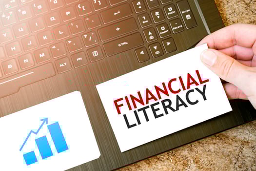 Calculator, red notepad, three colour pencils, silver pen and brown notebook with text FINANCIAL LITERACY photo