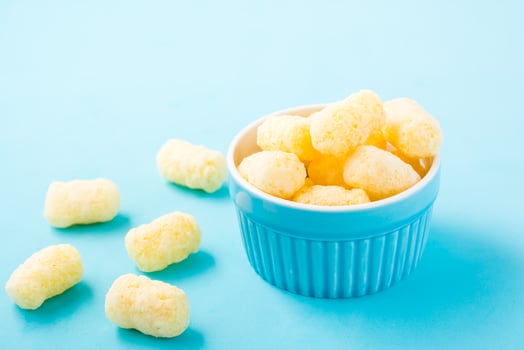 Corn sticks in powdered sugar in a bowl on a blue background. Children treat photo