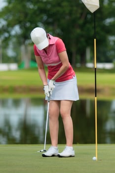 woman golfer approach for hitting golf ball on green photo