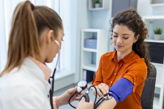 Measuring blood pressure. Young woman have a visit with female doctor in modern clinic. Measuring blood pressure. Pressure gauge. Hypertension and high heart rate photo