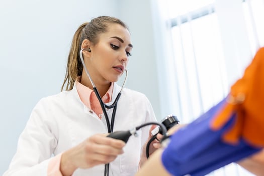 Doctor using sphygmomanometer with stethoscope checking blood pressure to a patient in the hospital. photo
