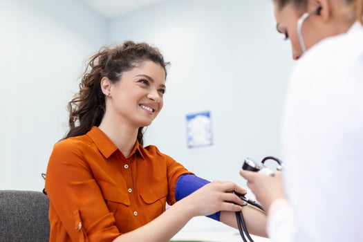 Nurse measuring blood pressure of a woman patient during an examination in the clinic. Doctor checking patient arterial blood pressure. Health care. photo