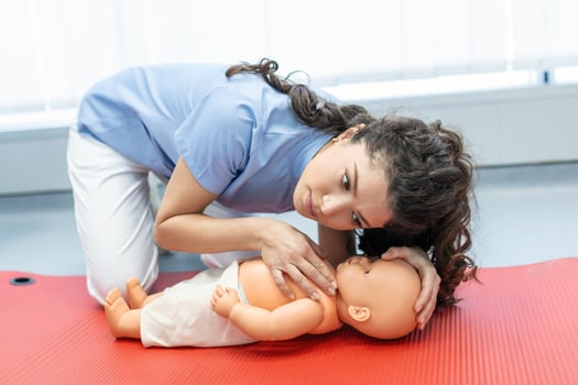 CPR practitioner examining airway passages on infant dummy. Model dummy lays on table and two doctors practice first aid. photo