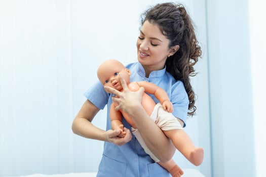 CPR practitioner examining airway passages on infant dummy. Model dummy lays on table and two doctors practice first aid. photo