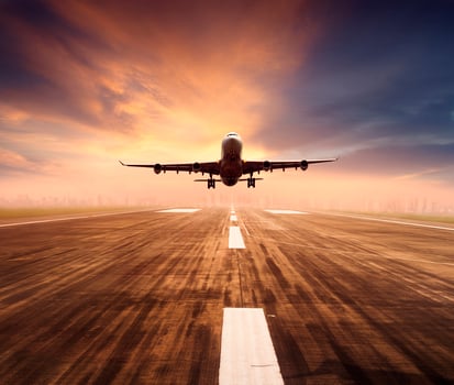 air plane flying over airport runway with city scape and sunset sky background photo