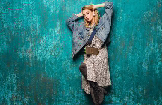 attractive stylish blonde woman in jeans oversize jacket walking against wall fashion photo