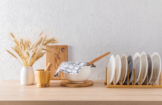 Wooden dryer with plates, a large bowl covered with a towel, various kitchen items in the interior of a modern kitchen in light colors. photo