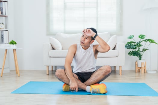 Online class training. Asian mature man tired in sportswear making stretching for legs on mat yoga and meditate in living room interior and smiling. Happy sportsman workout by him slef. Sport at home. photo