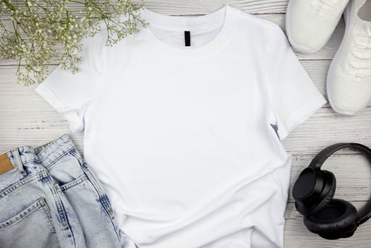 White womens cotton Tshirt mockup with flowers, jeans, sneakers and black headphones on wooden background. Design t shirt template, print presentation mock up. Top view flat lay. photo