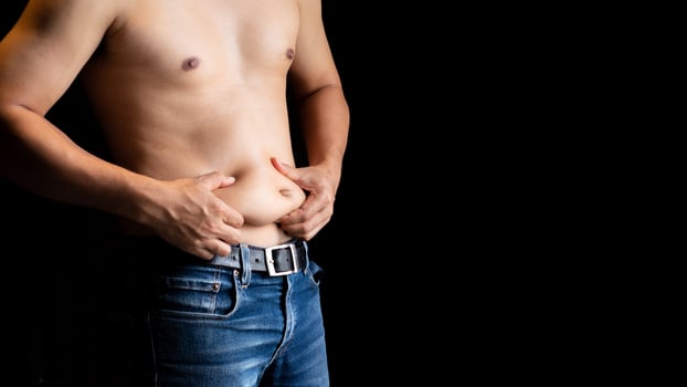 Body care concept  Shirtless man and hand pinching him excess belly fat, Fat unhealthy men cellulite  body isolated on black background photo