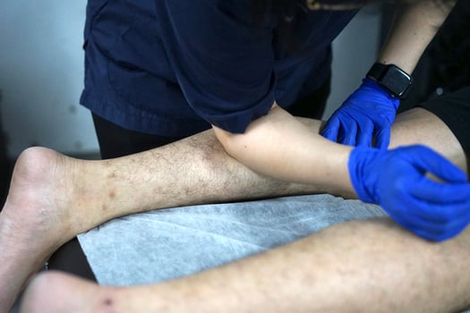 Muscle massage after a hard workout. Physical therapist treats injury of male patient athlete leg. Massage Gun Machine Recovery Therapy And Stimulation photo