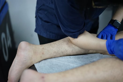 Muscle massage after a hard workout. Physical therapist treats injury of male patient athlete leg. Massage Gun Machine Recovery Therapy And Stimulation photo