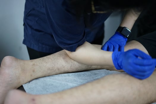 Muscle massage after a hard workout. Physical therapist treats injury of male patient athlete leg. Massage Gun Machine Recovery Therapy And Stimulation photo