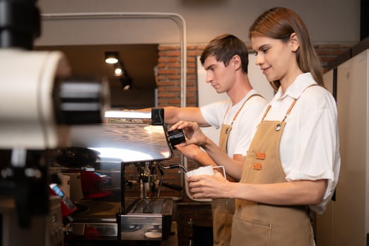 Barista pouring coffee into a cup in coffee shop, closeup photo