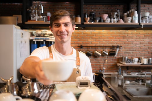 Portrait of a smiling male barista holding a cup of coffee photo