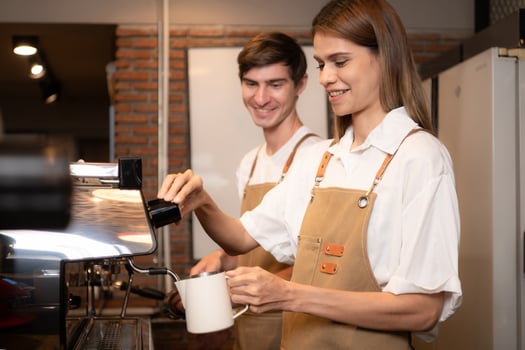 Barista pouring coffee into a cup in coffee shop, closeup photo
