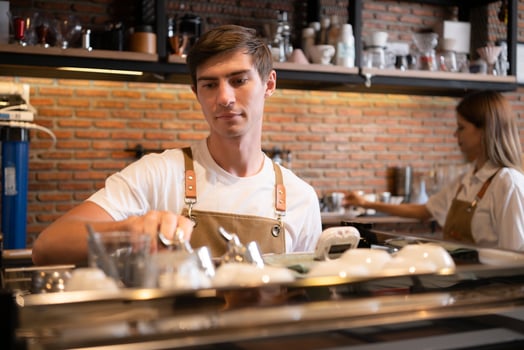 Barista working in cafe. Portrait of young male barista standing behind counter in coffee shop. photo