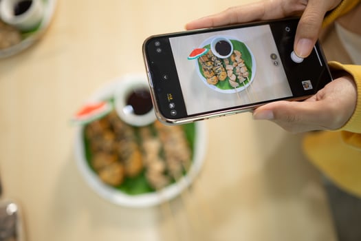 Woman taking photo of mushroom food with smartphone at table in healthy restaurant