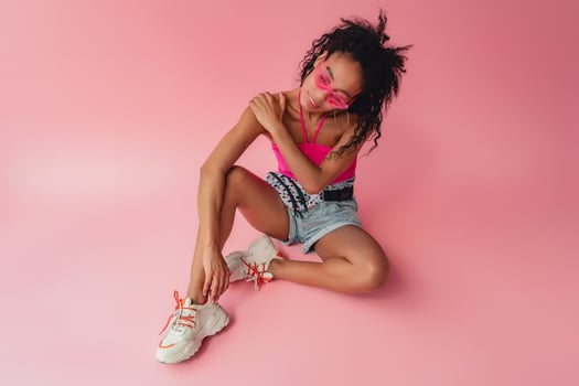 attractive black african american woman in stylish outfit on pink background photo