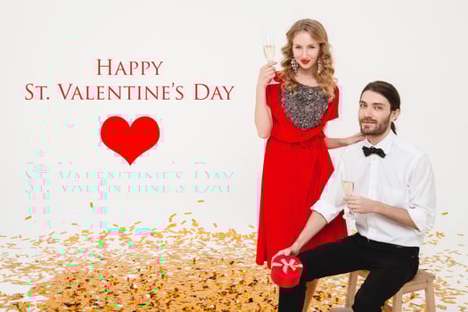 beautiful stylish couple in love celebrating, isolated white studio background, golden confetti, red dress, elegant style, drinking champagne, holding glasses, present box, smiling, happy, valentine's photo