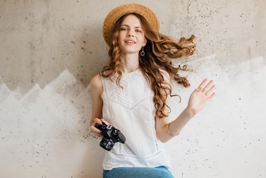 young pretty smiling happy woman in straw hat holding vintage photo camera, long curly hair