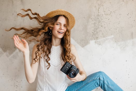young pretty woman in summer vacation style outfit holding vintage photo camera