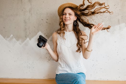 young pretty woman in summer vacation style outfit holding vintage photo camera
