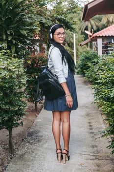 young stylish woman walking, listening to music on headphones photo