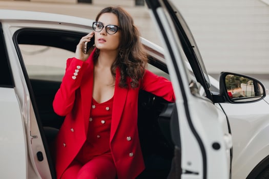 beautiful sexy rich business woman in red suit sitting in white car, wearing glasses photo