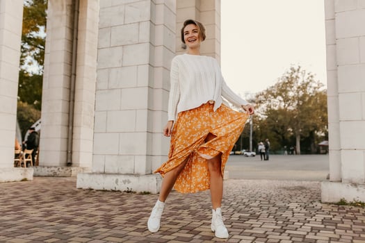 young pretty happy smiling woman in yellow printed dress and knitted white sweater photo