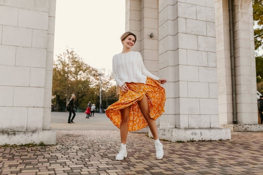 young pretty happy smiling woman in yellow printed dress and knitted white sweater photo