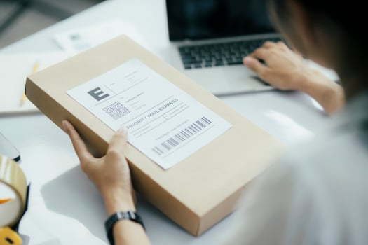 Young business owner putting shipping label on parcel. photo