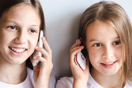 Two cheerful girls are talking on white old-fashioned push-button telephones photo