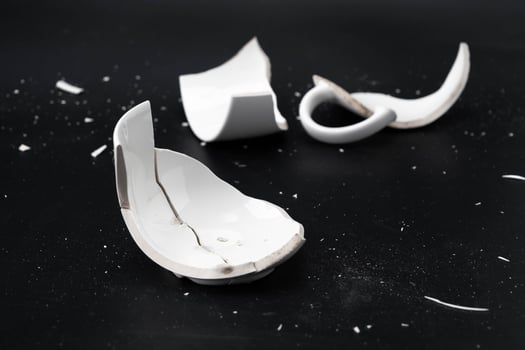 Large white mug with cracks. White cup for tea or soup with cracks isolated on dark background. Broken ceramic cup close up. symbol of divorce or loss photo