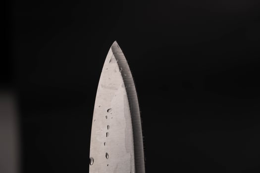 Water drop on sharp knife isolated on dark background. water splashing on knife. photo