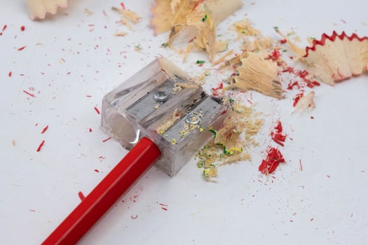 Colored pencils or pencils and sharpener isolated on white background. Red wooden pencil and pencil shavings on white table. photo
