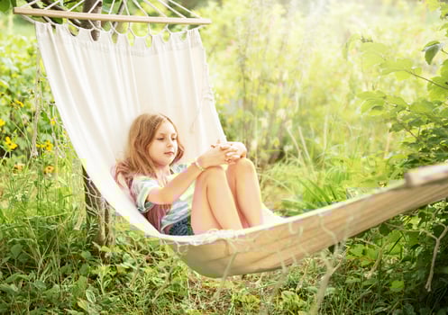 A little girl rests in a hammock and eats cherries in the summer. photo