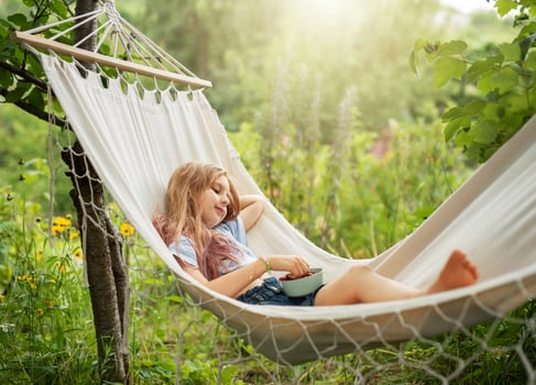 A little girl rests in a hammock and eats cherries in the summer. photo