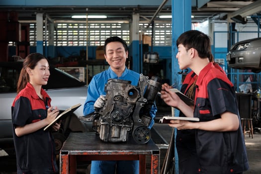 Specialist lecture, a male supervisor engineer train and describe automotive engines with mechanic worker staff teams for repair work at car service garage and maintenance jobs in automobile industry. photo