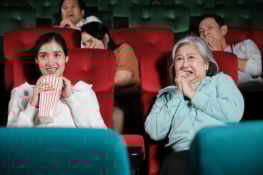 Various people in theater. Asian senior woman and many audiences are scared of watching thriller and horror cinema, frightened together on movie stage, and entertainment lifestyle with film show. photo