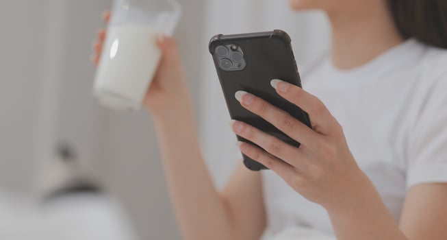 Efficient Young Millennial Girl Sitting on a Bed in the Morning, Uses Laptop Computer and Eats Croissants and Drinks Coffee for Breakfast photo
