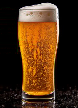 A glass of cold fresh beer with cap of foam. Splash of foam with tasty american beer. Beer day concept by AI Generated photo