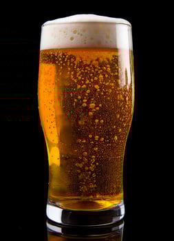 A glass of cold fresh beer with cap of foam. Splash of foam with tasty american beer. Beer day concept by AI Generated photo