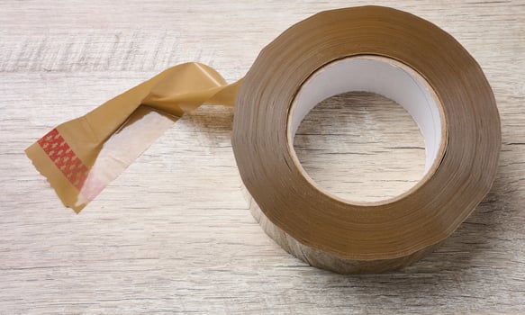 Roll of brown tape on a wooden table, top view photo