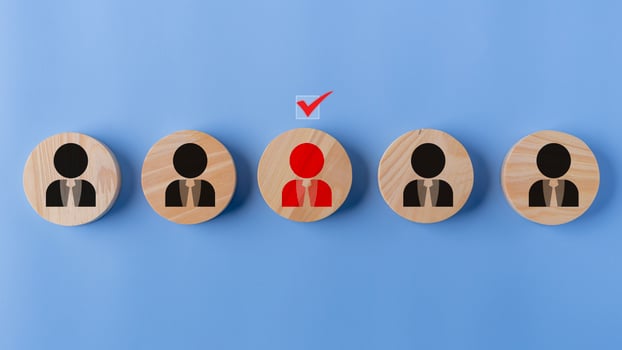 Wooden figures of people on a blue background with a red check mark. Online recruitment application specialist search service concept photo